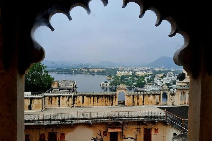 A view of Lake Pichola and its surrounding architecture framed by an ornate archway.
