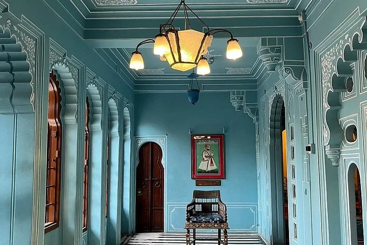 A hallway with blue walls, arched windows, and a framed portrait of a ruler.