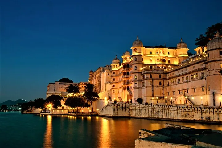 City Palace illuminated at night, reflecting beautifully on the waters of Lake Pichola.